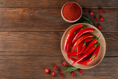Bowl of ground red pepper with ingredients on wooden table, flat lay. Space for text