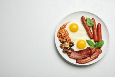 Photo of Traditional English breakfast with fried eggs on white table, top view. Space for text