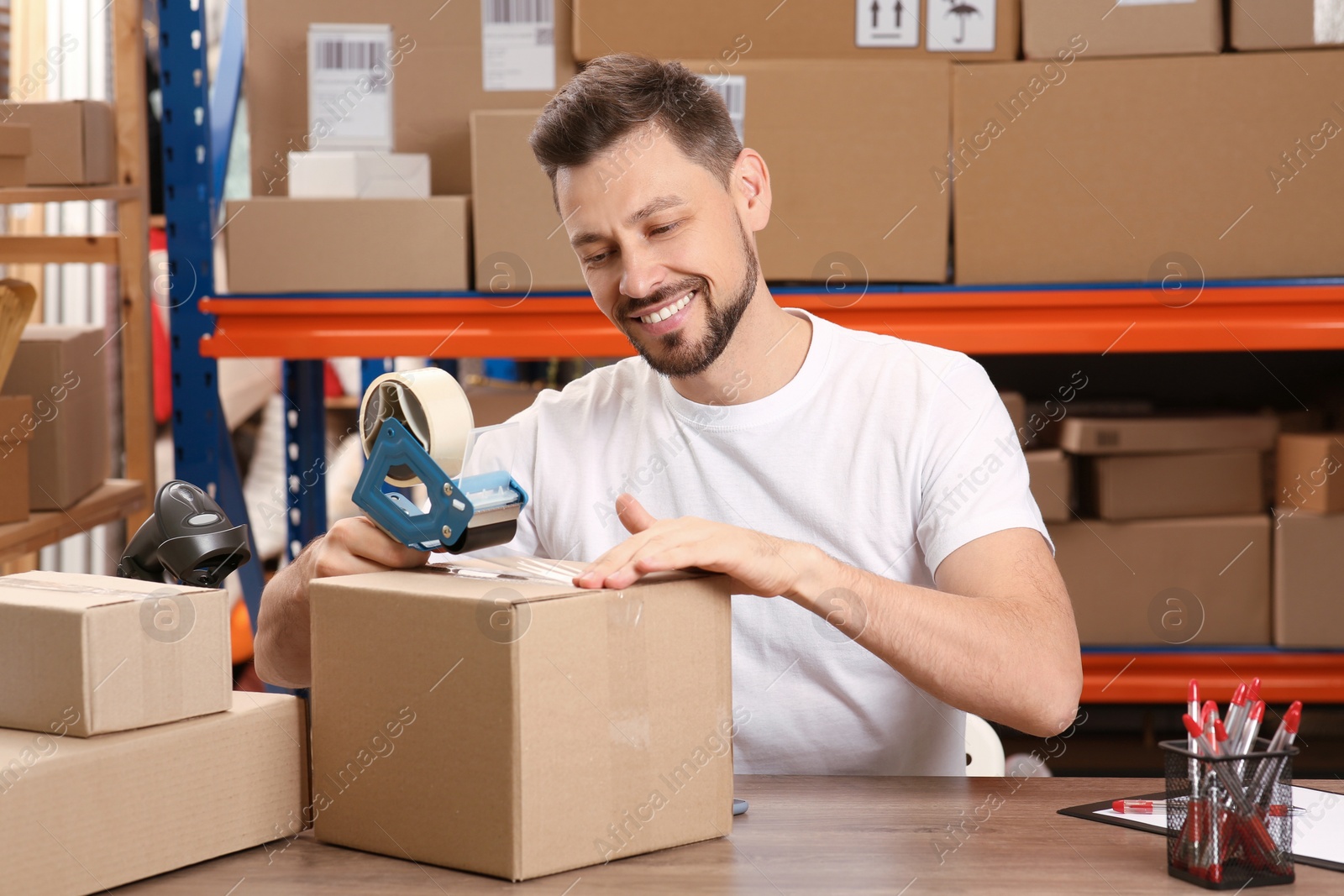 Photo of Post office worker packing parcel at counter indoors
