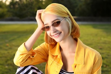 Beautiful young woman with bright dyed hair in park