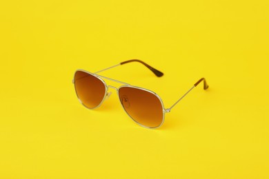 Photo of Stylish pair of sunglasses on yellow background