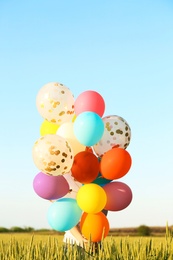 Photo of Young woman with colorful balloons in field on sunny day