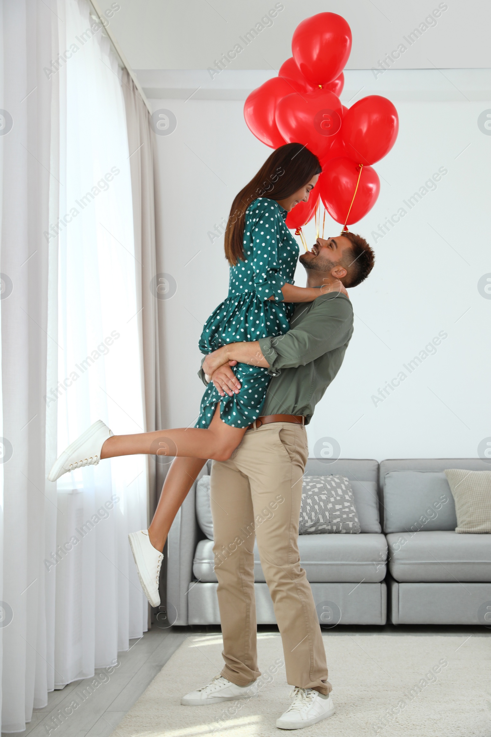 Photo of Young couple with air balloons at home. Celebration of Saint Valentine's Day