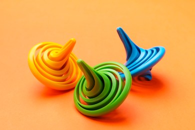 Many colorful spinning tops on orange background, closeup