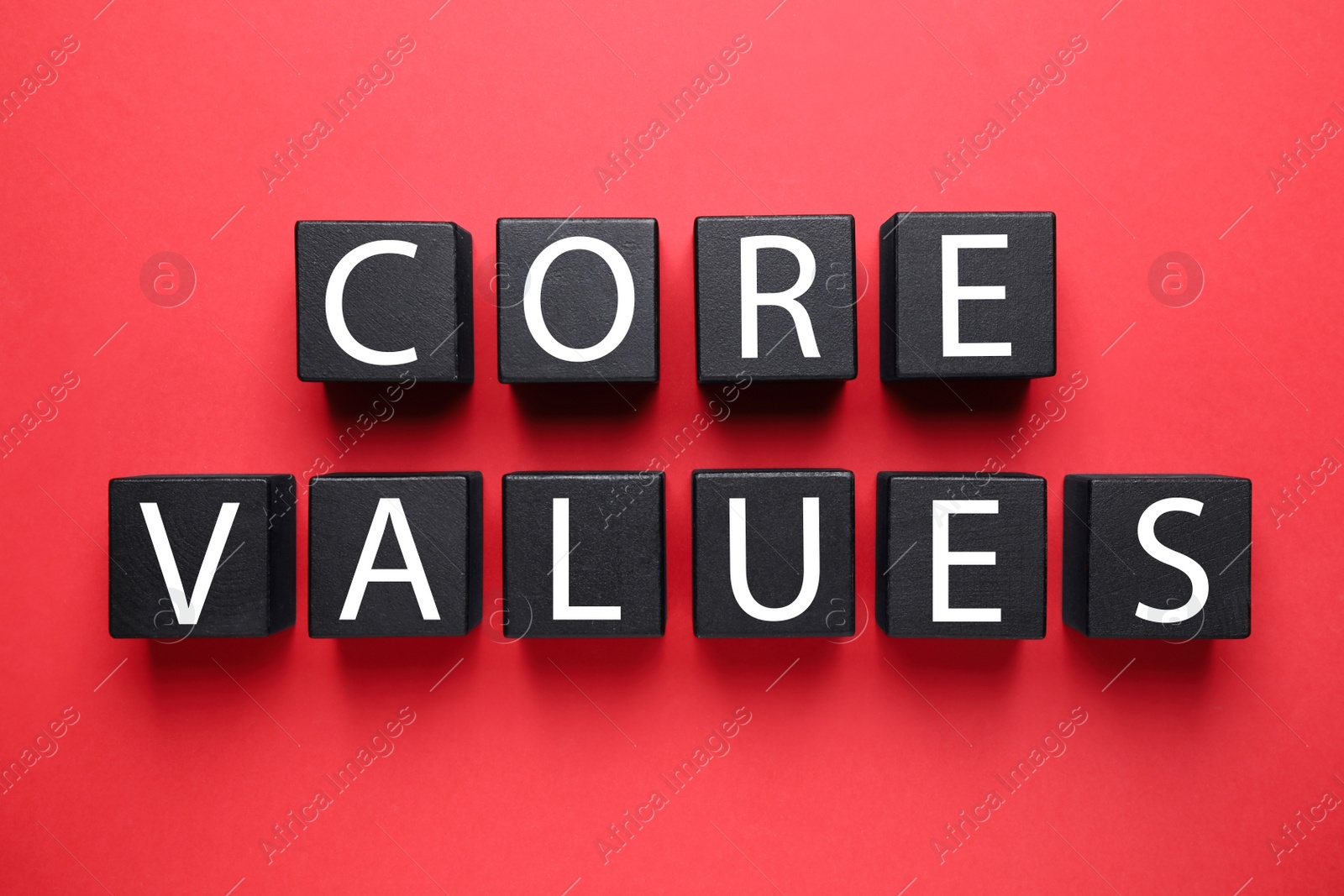 Photo of Black wooden cubes with phrase CORE VALUES on red background, flat lay