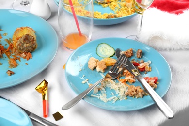 Photo of Plates with food leftovers on white tablecloth after party