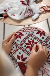 Woman embroidering white shirt with colorful threads in hoop, closeup. Ukrainian national clothes