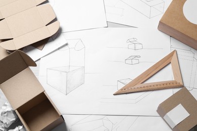 Photo of Creating packaging design. Drawings, boxes and stationery on table, above view