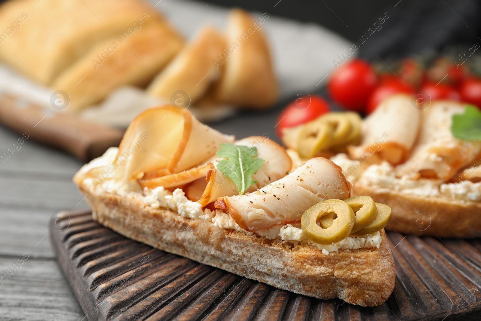 Photo of Board with delicious chicken bruschettas on table, closeup