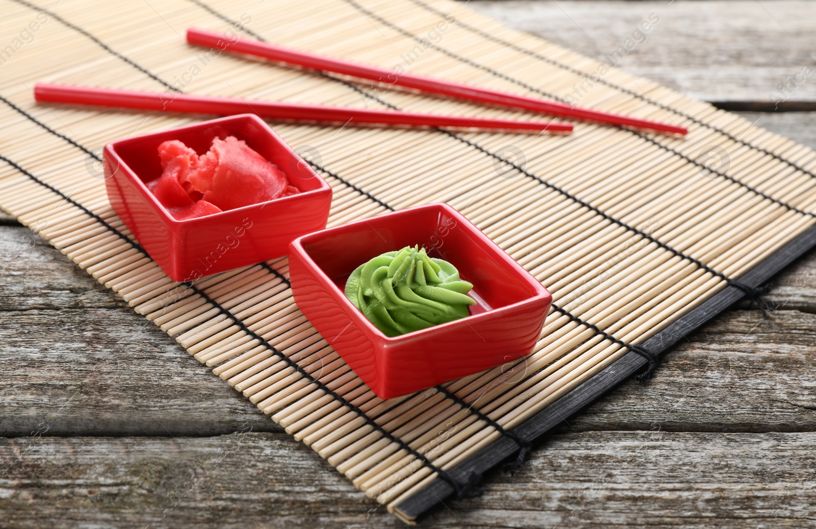 Photo of Swirl of wasabi paste, pickled ginger, chopsticks and bamboo mat on wooden table