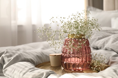 Photo of Vase with bouquet of beautiful Gypsophila flowers on bed indoors