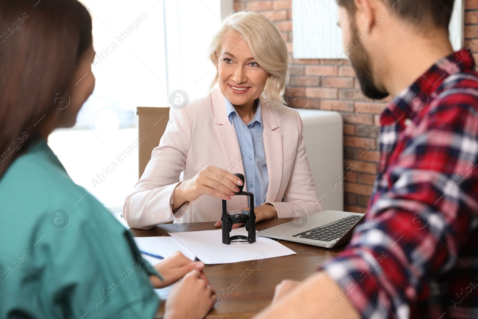 Photo of Female notary working with young couple in office
