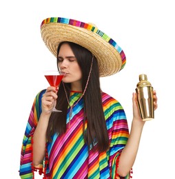 Young woman in Mexican sombrero hat and poncho drinking cocktail on white background
