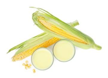 Photo of Tasty fresh corn milk in glasses and cobs on white background, top view