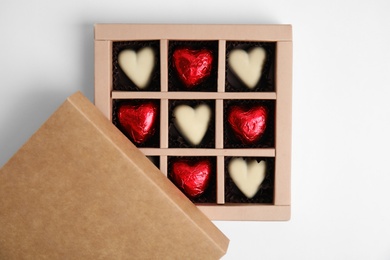 Tasty heart shaped chocolate candies on white background, top view. Happy Valentine's day