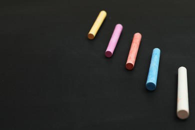 Photo of Colorful chalks on black board, space for text
