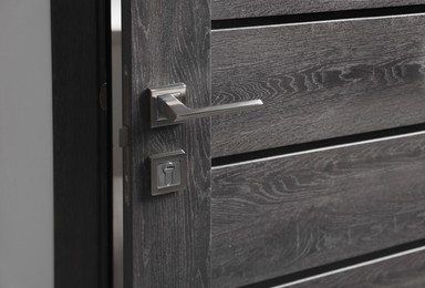 Photo of Dark wooden door with metal handle, closeup