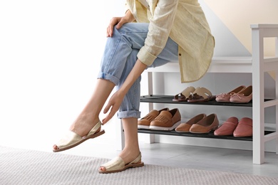 Woman putting on shoes indoors, closeup. Stylish hallway interior