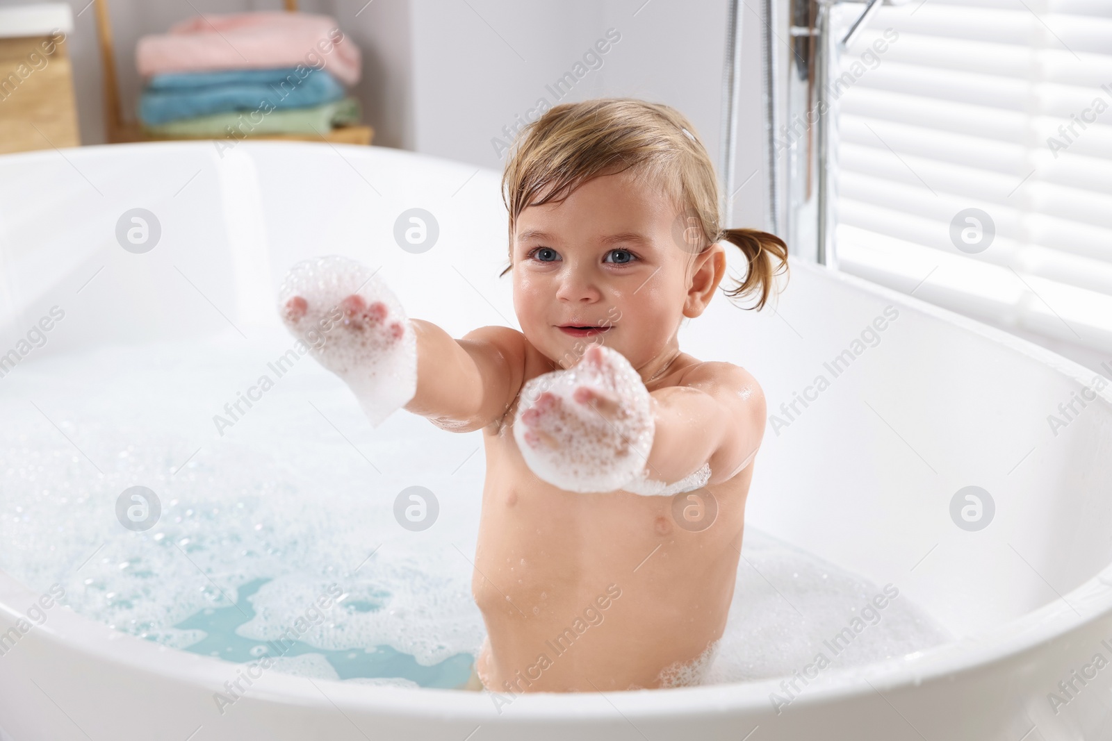 Photo of Cute little girl taking foamy bath at home