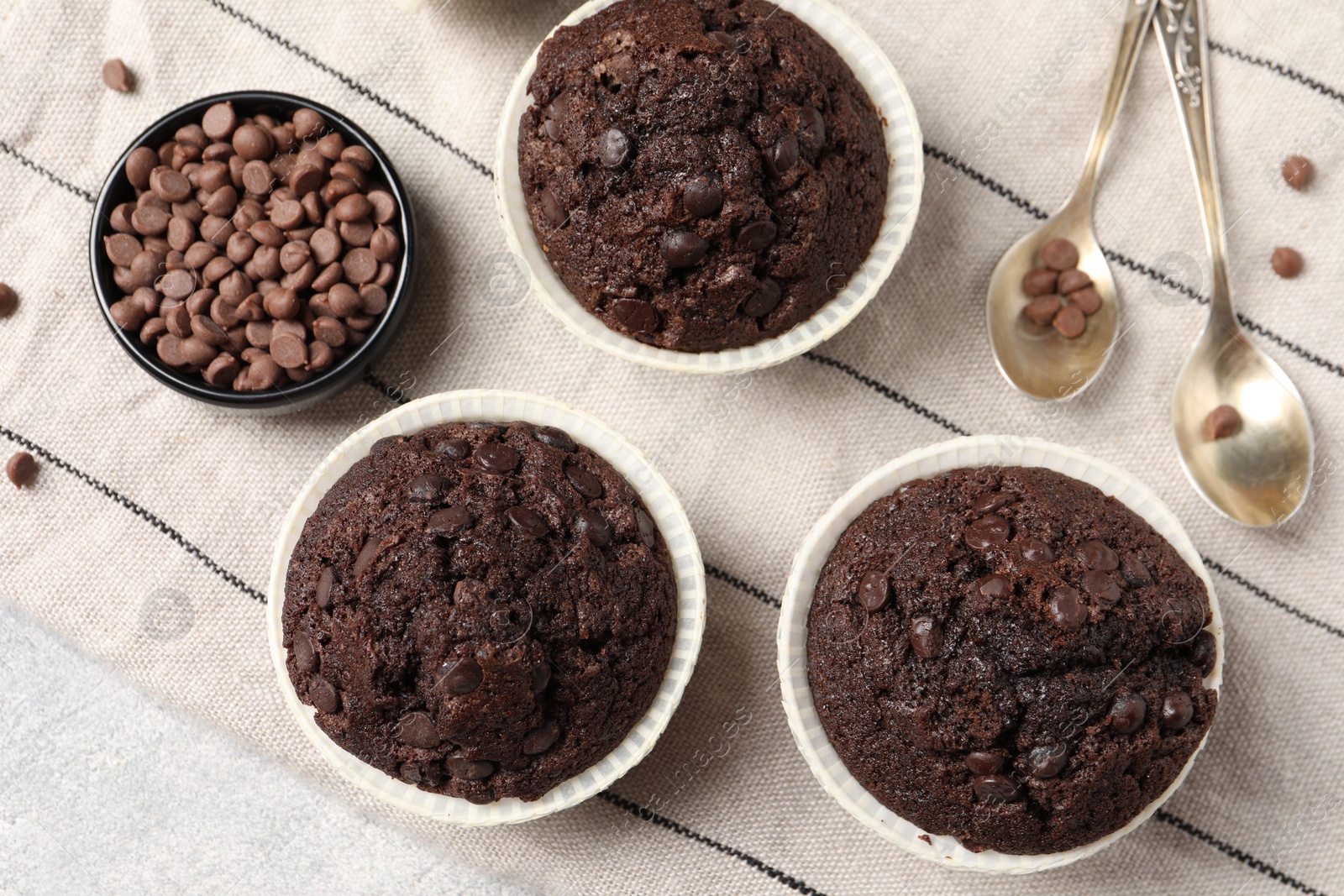 Photo of Tasty chocolate muffins and cloth on table, flat lay