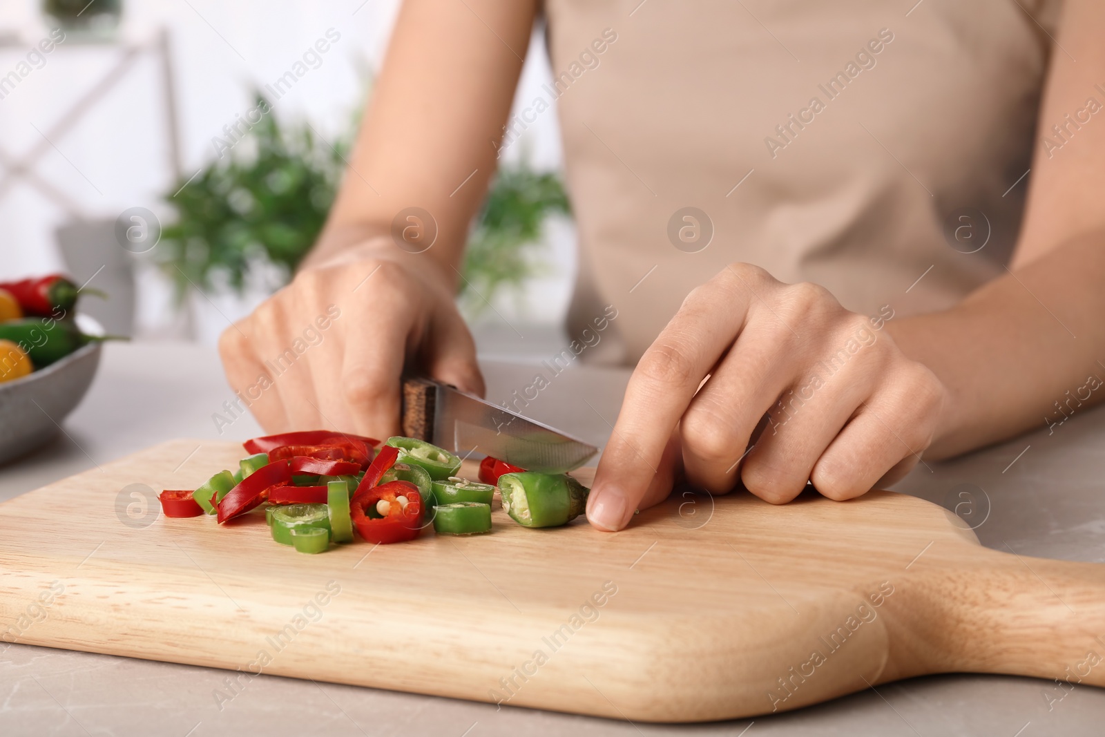 Photo of Woman cutting chili peppers at table, closeup