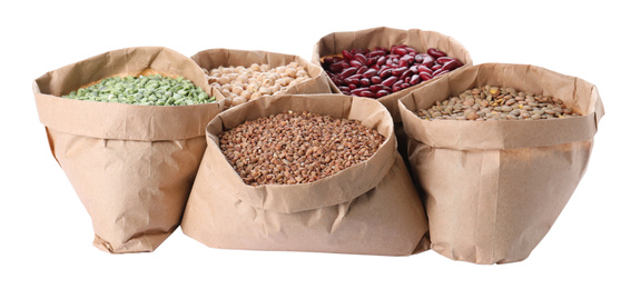 Photo of Different types of legumes and cereals in paper bags on white background. Organic grains