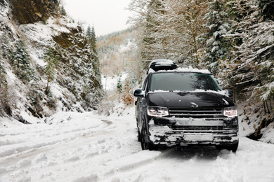 Photo of Modern car on snowy road near forest. Winter vacation