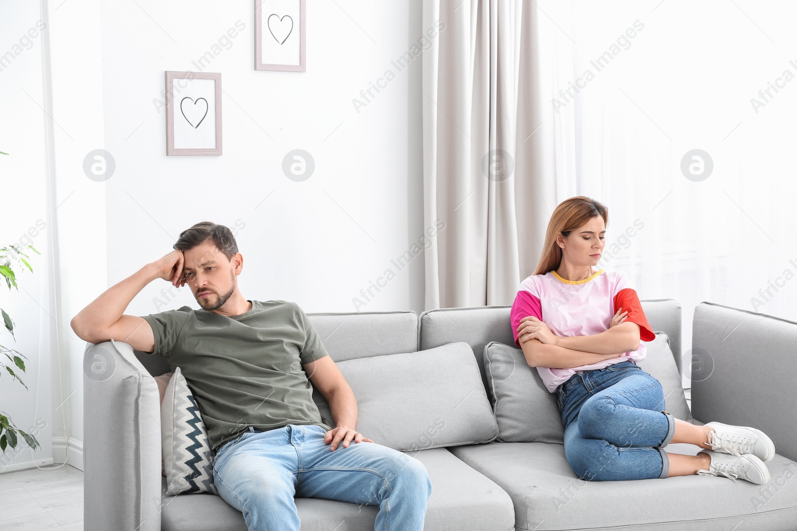 Photo of Couple ignoring each other after argument in living room. Relationship problems