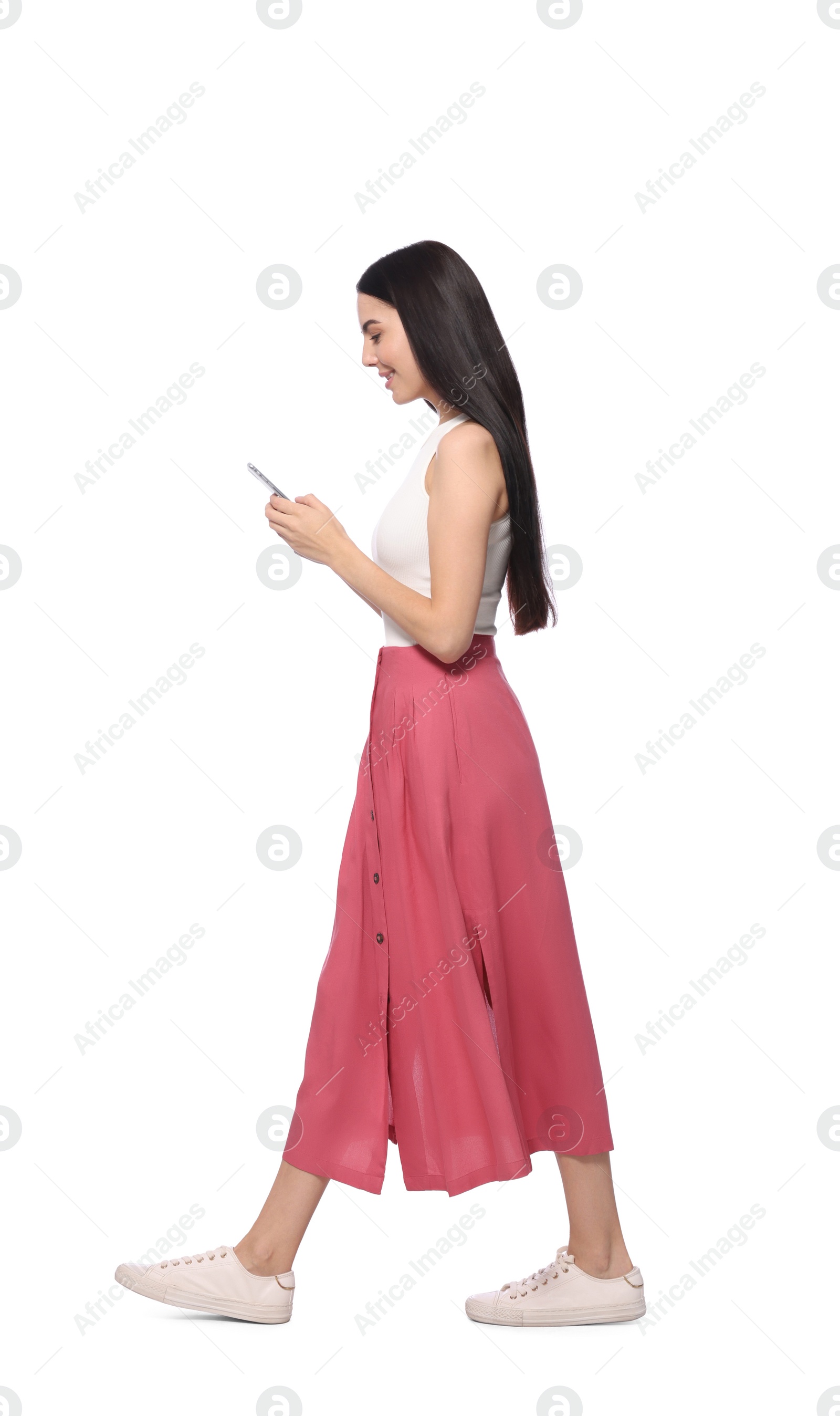 Photo of Young woman using smartphone while walking on white background