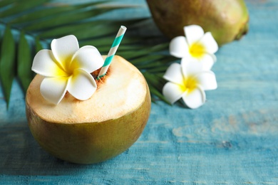 Fresh green coconut with drinking straw on wooden table