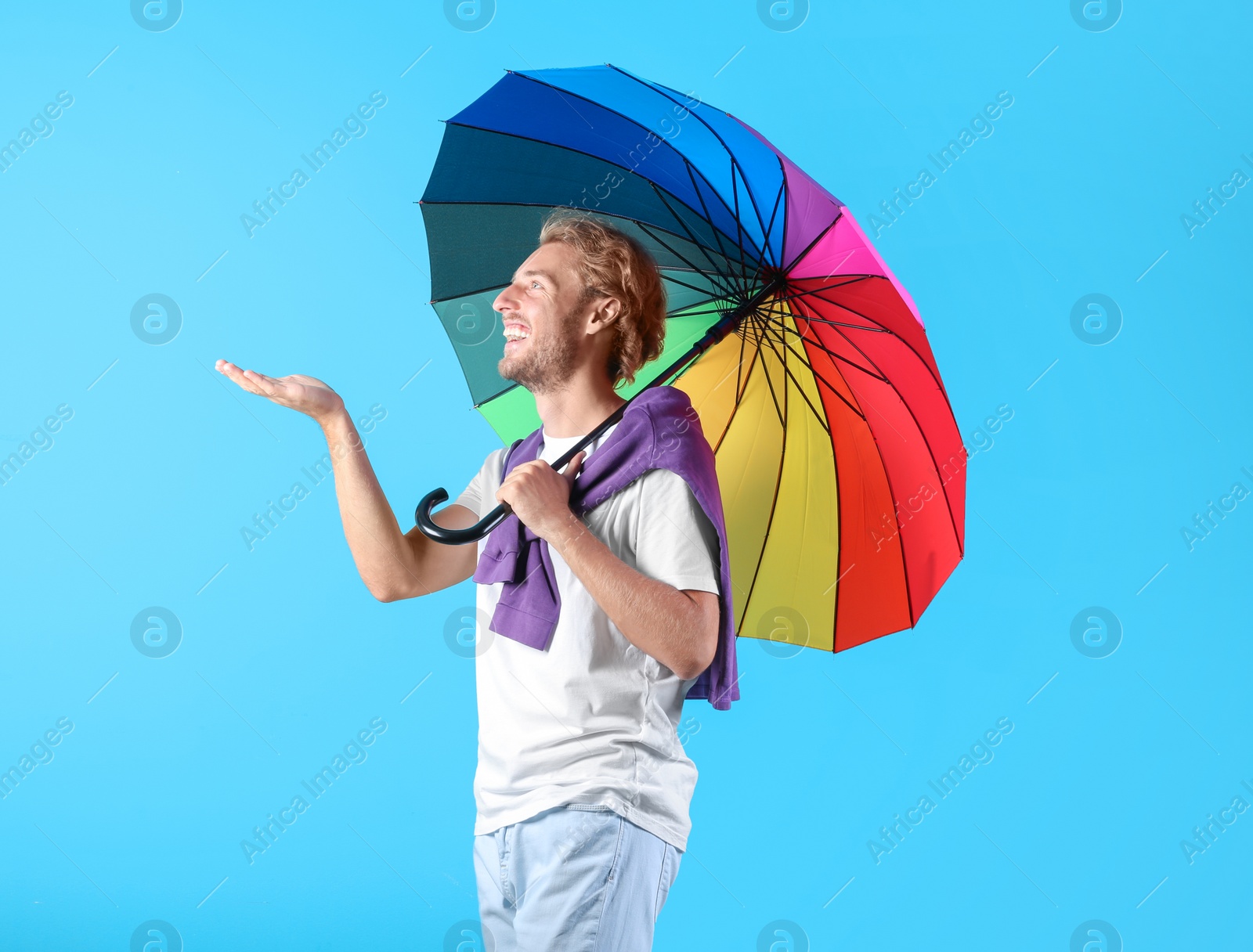 Photo of Man with rainbow umbrella on color background