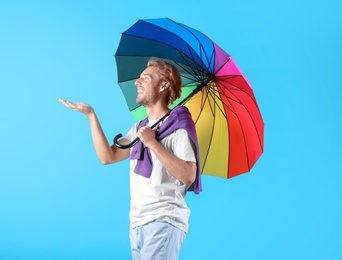 Photo of Man with rainbow umbrella on color background