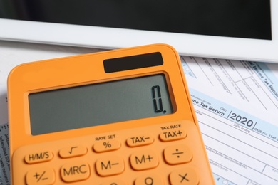 Photo of Calculator, tablet and documents on table, closeup. Tax accounting