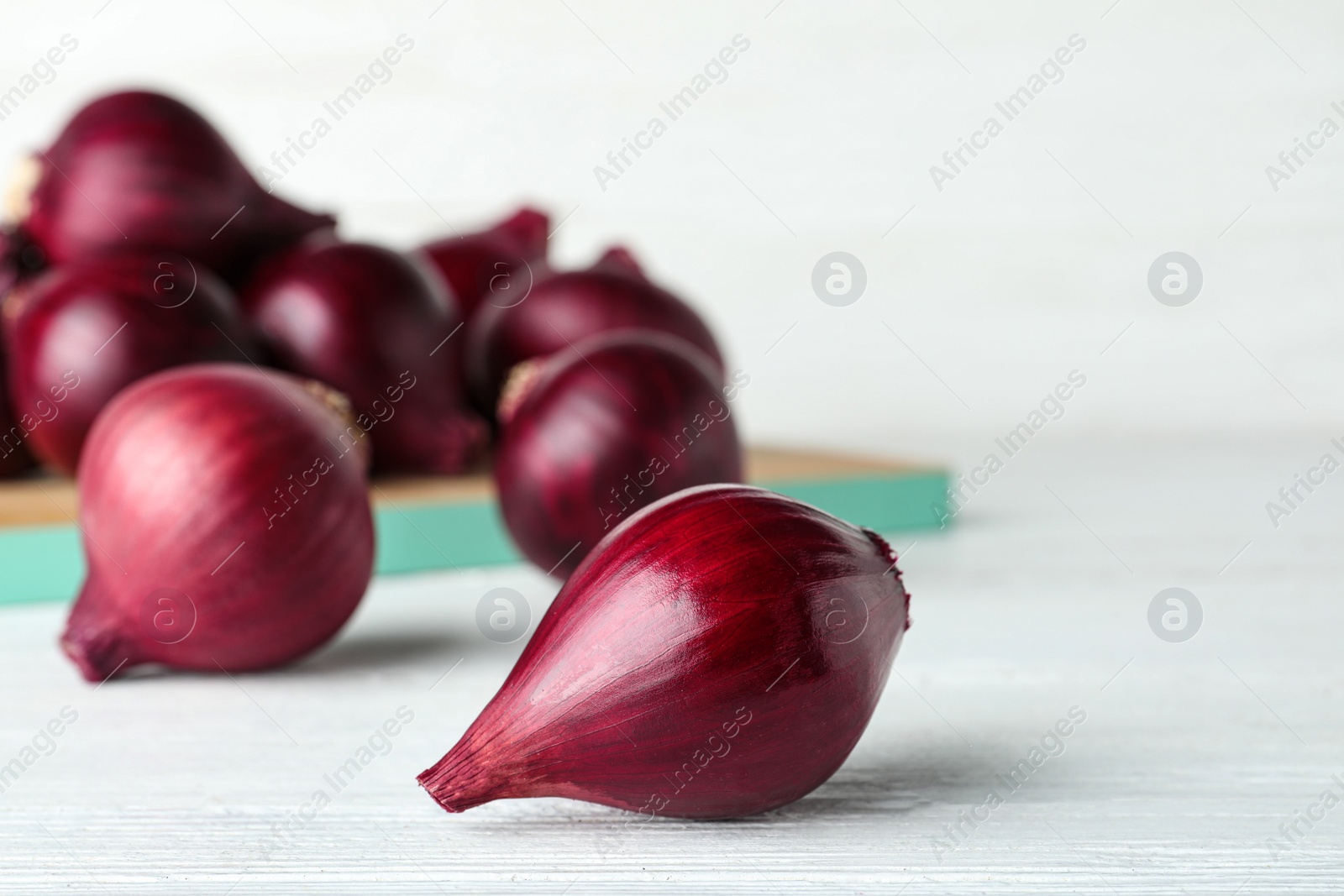 Photo of Ripe red onion bulbs on white wooden table