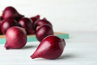 Photo of Ripe red onion bulbs on white wooden table