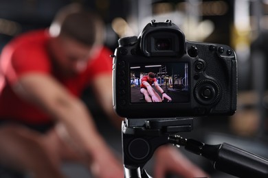 Photo of Man recording workout at gym, focus on camera. Online fitness trainer