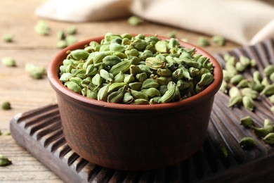 Bowl of dry cardamom pods on wooden table, closeup