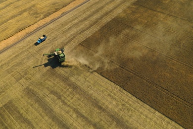 Photo of Beautiful aerial view of modern combine harvester working in field on sunny day. Agriculture industry