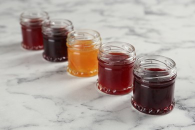 Photo of Jars of different jams on white marble table
