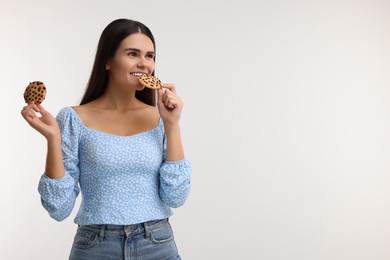 Young woman with chocolate chip cookies on white background, space for text