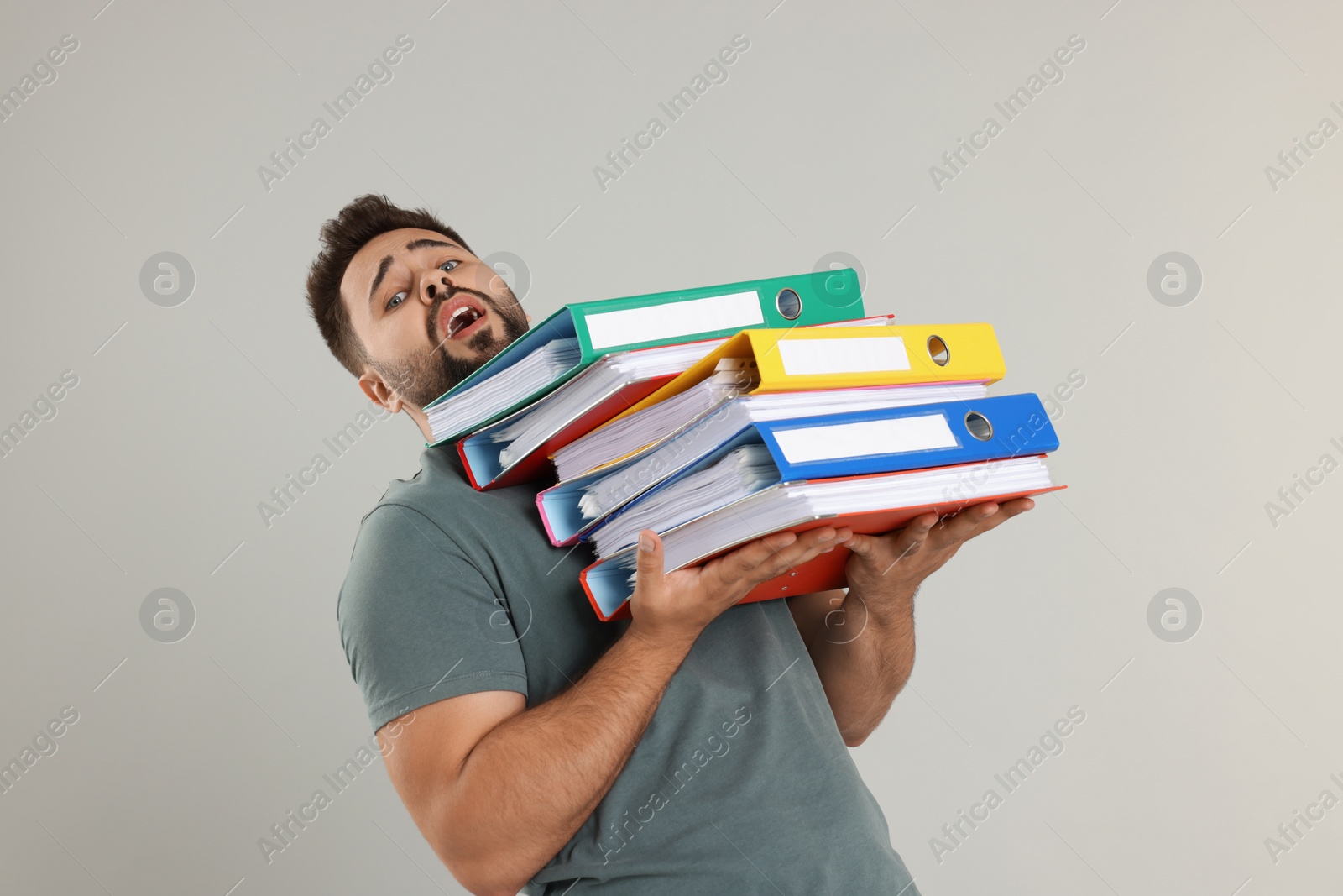 Photo of Stressful man with folders on light gray background