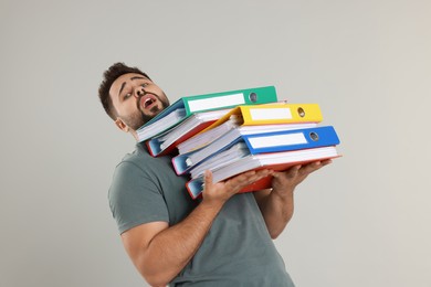 Photo of Stressful man with folders on light gray background