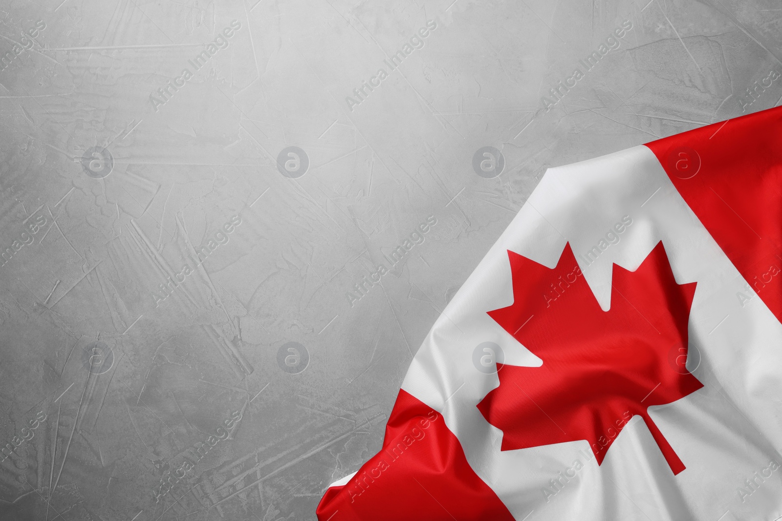 Photo of Flag of Canada on light grey stone table, top view. Space for text