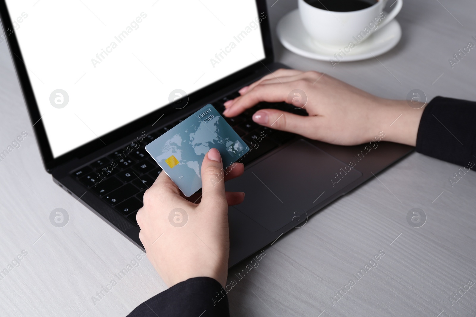 Photo of Online payment. Woman with laptop and credit card at white wooden table, closeup