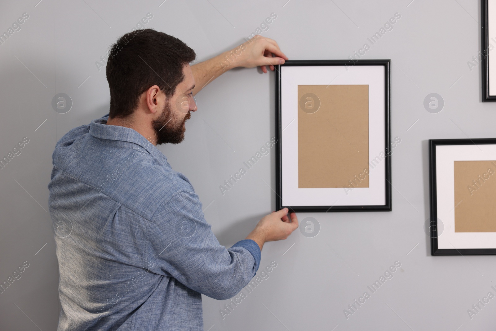 Photo of Man hanging picture frame on gray wall