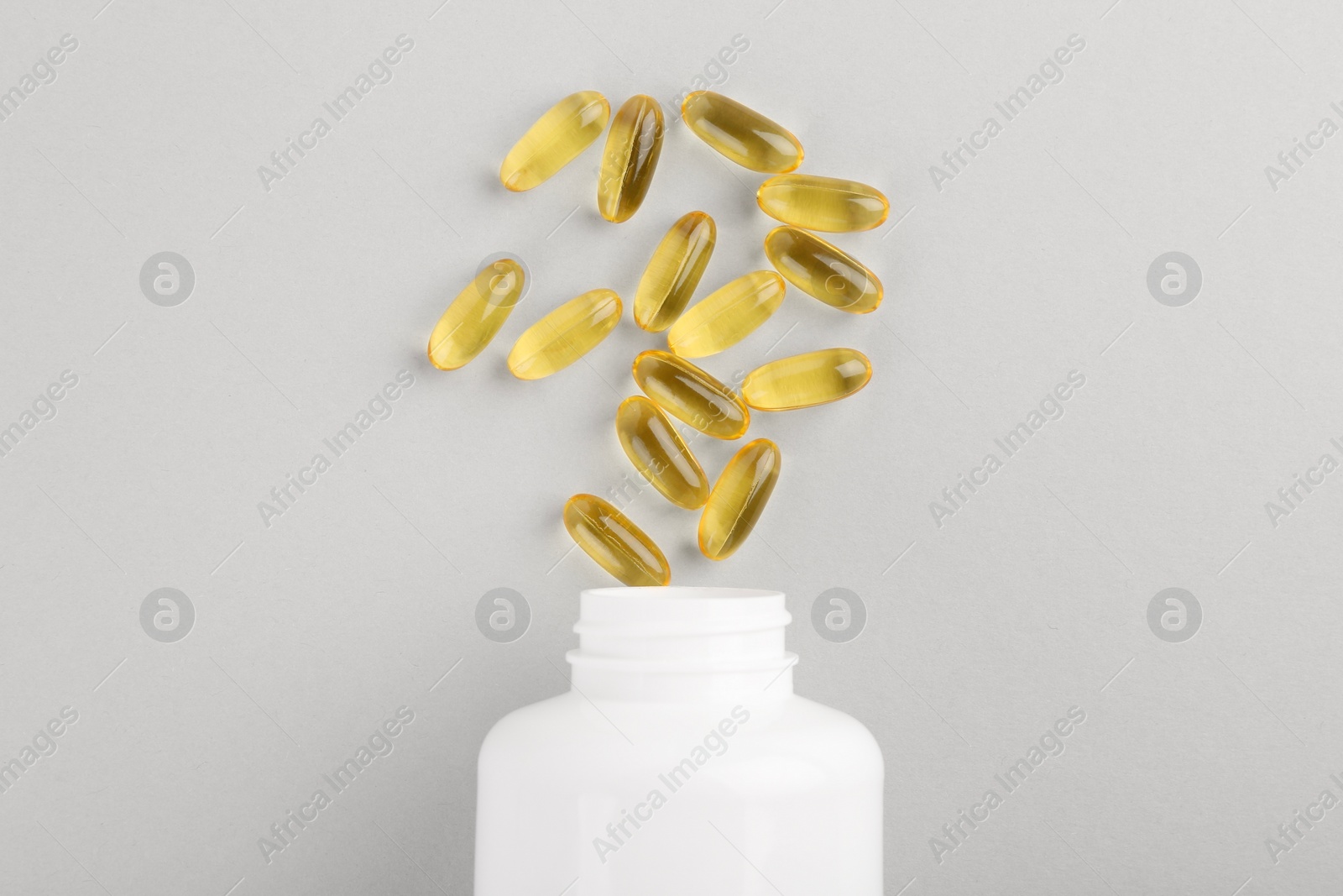 Photo of Bottle and vitamin capsules on light grey background, top view