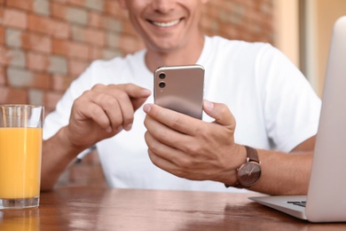 Photo of Man with modern smartphone in cafe, closeup