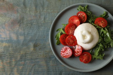 Photo of Delicious burrata cheese with tomatoes and arugula on grey wooden table, top view. Space for text