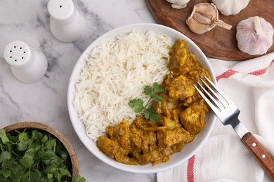 Photo of Delicious chicken curry with rice and ingredients on white marble table, flat lay