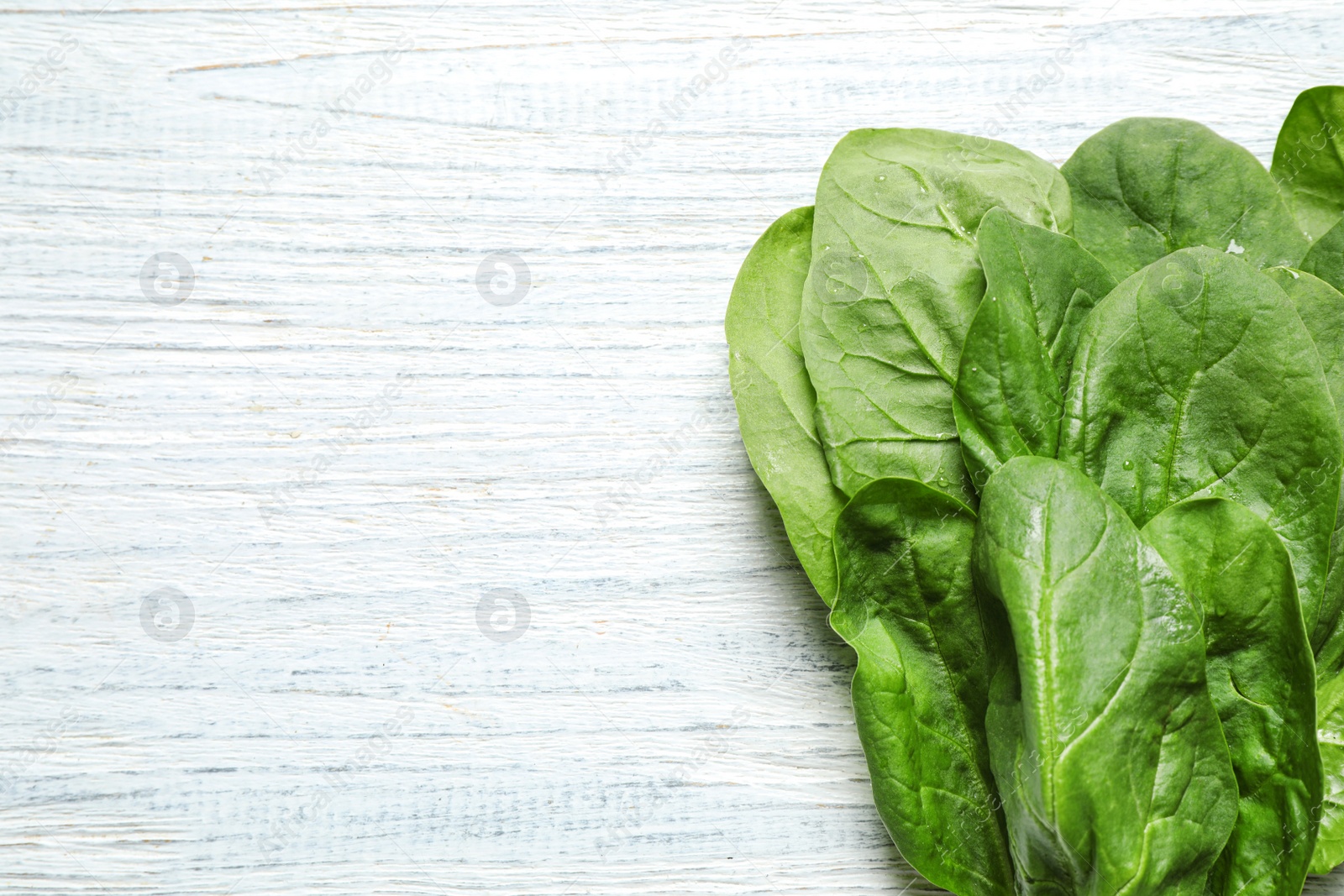 Photo of Fresh green healthy spinach on white wooden table, top view. Space for text